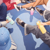 People sitting on a blue floor with colorful shoes and toys.