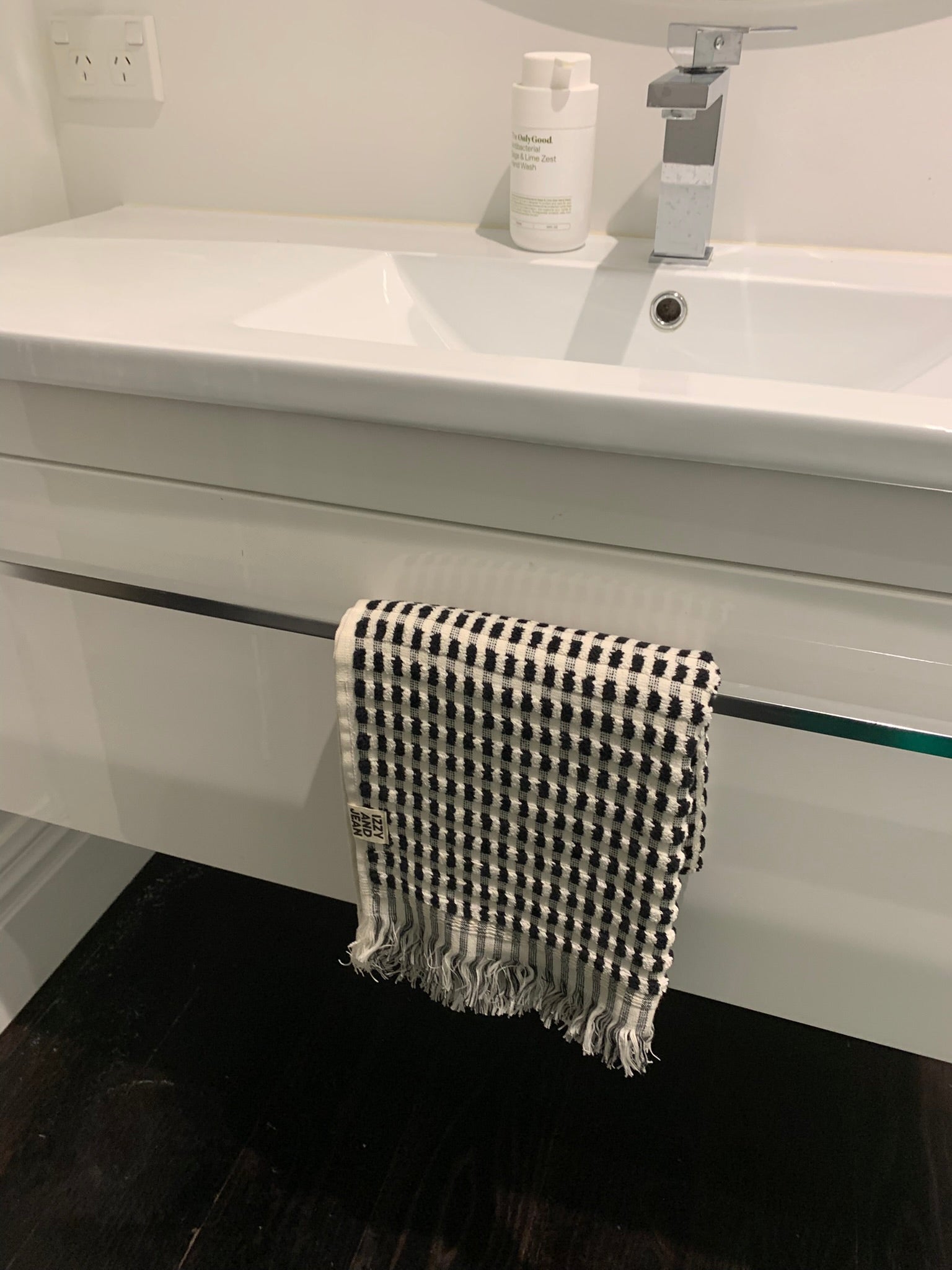 A black and white dotted cotton bath towel hanging on a towel rail on a bathroom sink