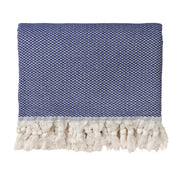 A dark blue throw blanket with a herringbone pattern and fringed edges on one end, laid flat.
