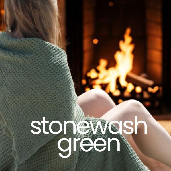 Person wrapped in a green blanket sitting by a fireplace with 'stonewash green' text overlay.