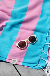 The Santorini Hot pink and marine Turkish towel with white sunglasses on top.
