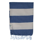 A folded striped Santorini Turkish towel with navy and sand colours, featuring white fringes on the edges.