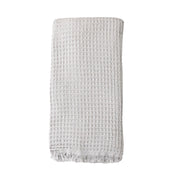 A pale grey coloured waffle bath towel folded on a white background