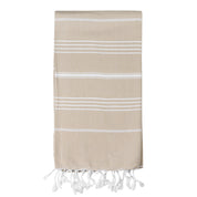A beige/sand coloured Turkish towel with white stripes and tassels on the bottom edge.